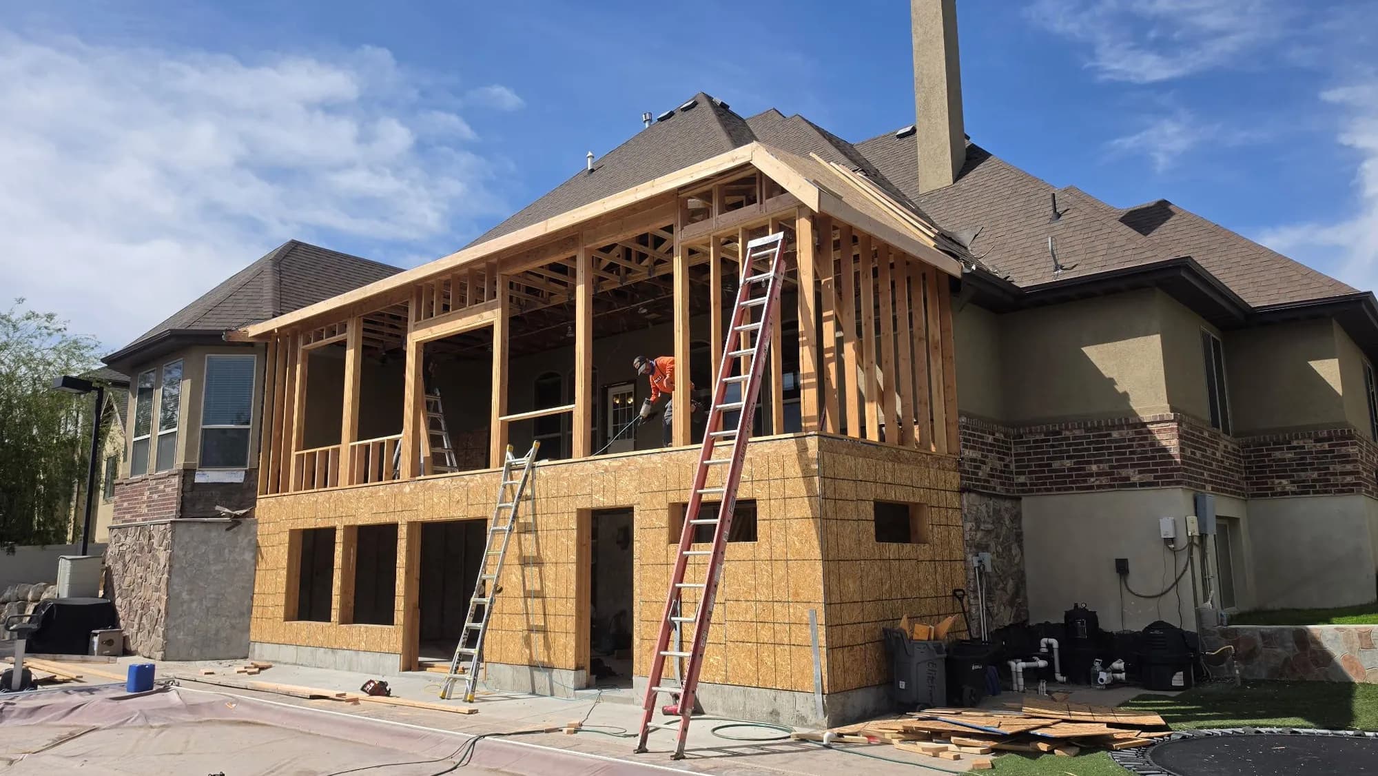 Rear of house with two-story addition framing, ladders on site