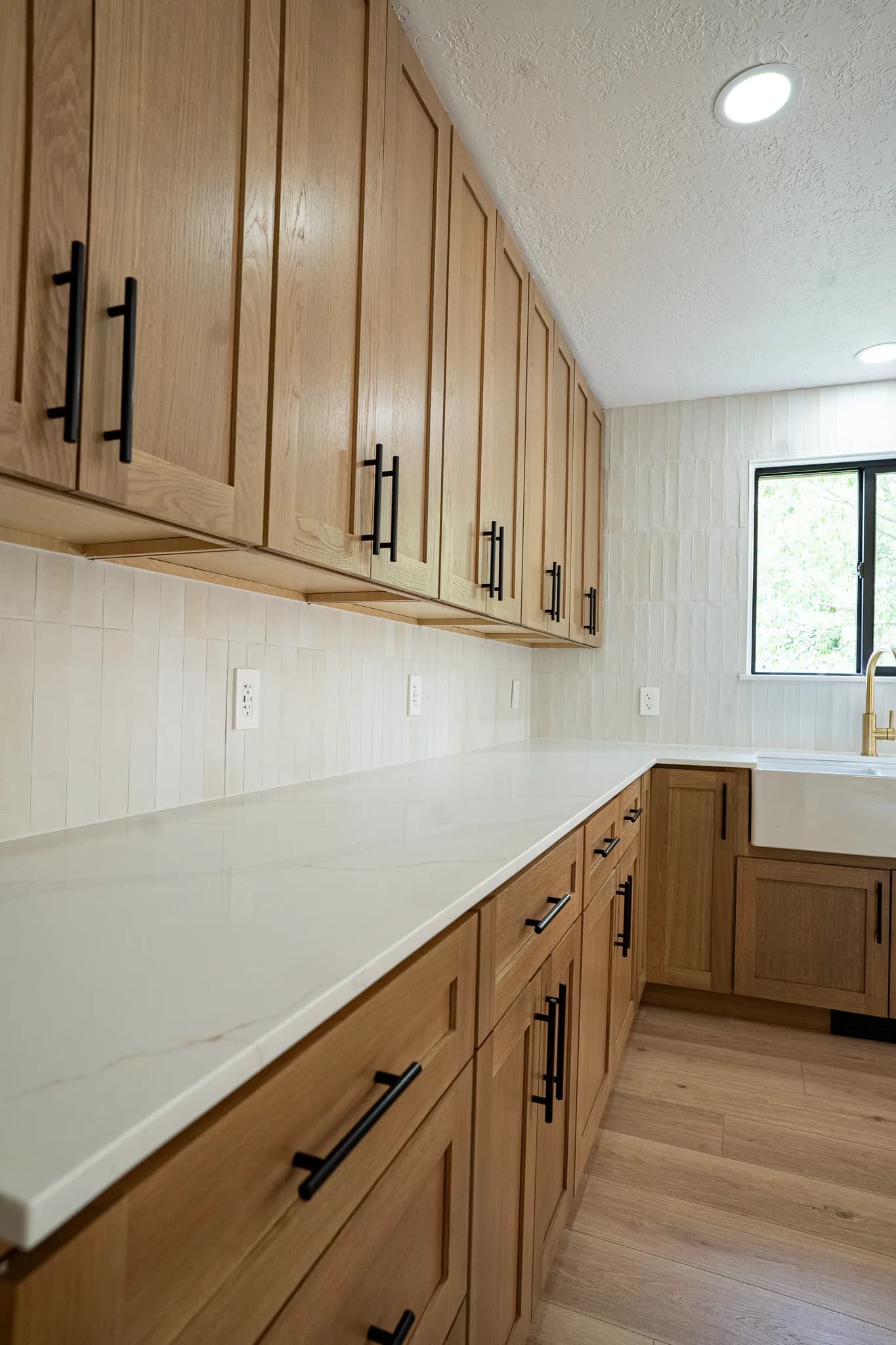 Green cabinets, a white farmhouse sink, and brass lanterns over the island